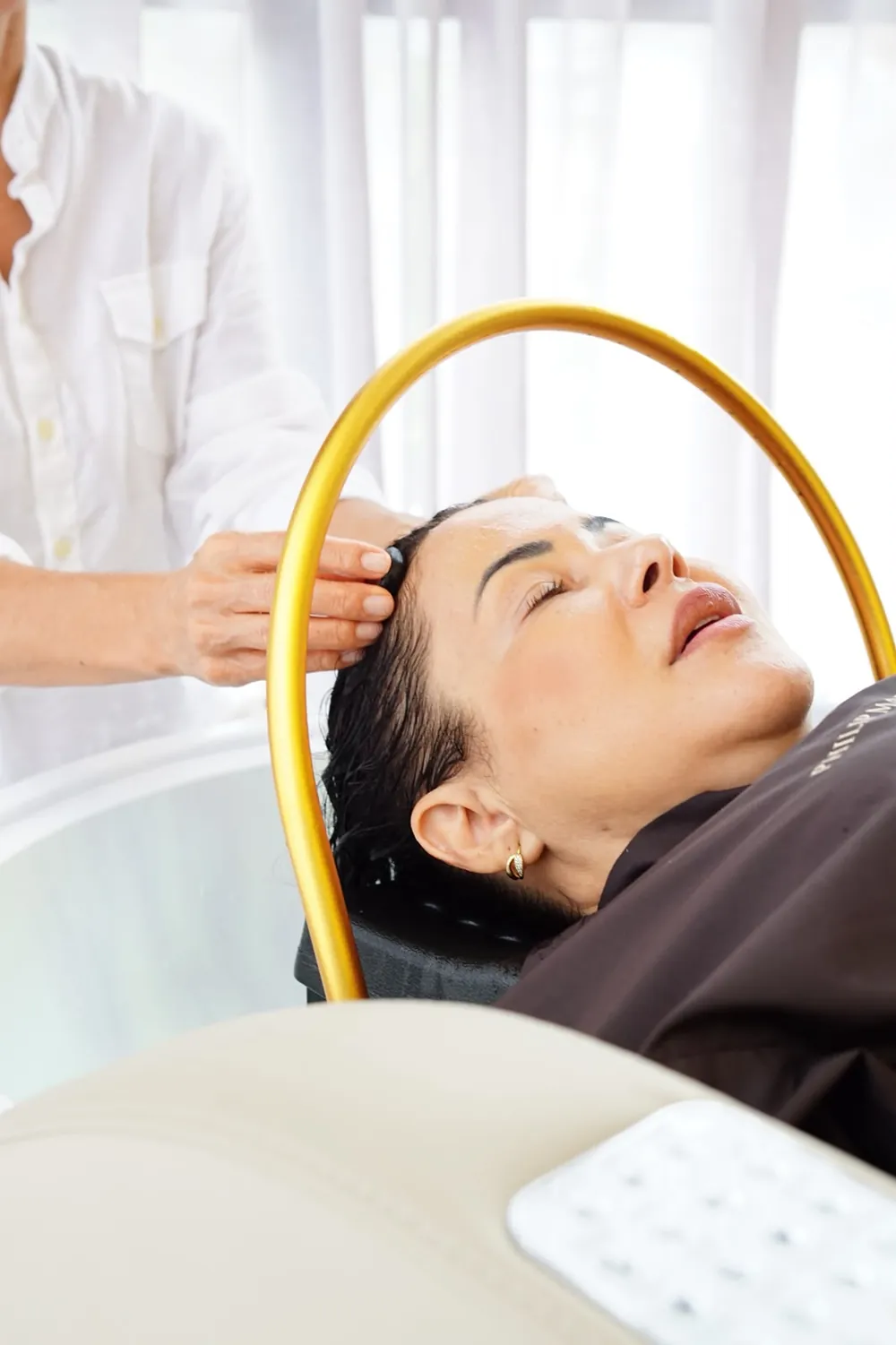Cliente de olhos fechados no lavatório do DENIV, recebendo massagem no couro cabeludo
